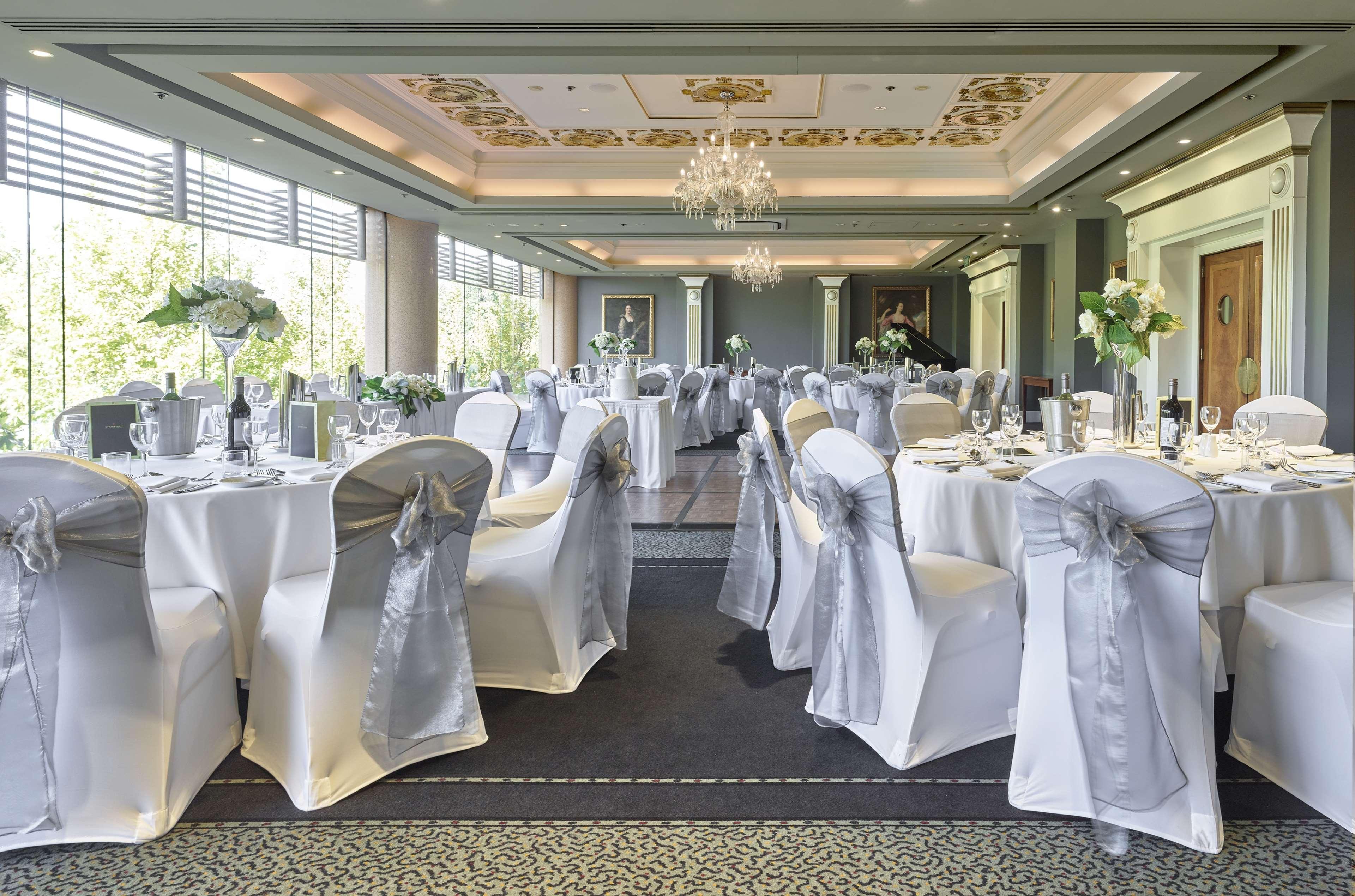 Stamford Plaza Adelaide Hotel Ngoại thất bức ảnh The photo displays an elegantly arranged banquet hall. The room features several round tables covered with white tablecloths, each adorned with silver sashes on the chairs. There are floral centerpieces, possibly white flowers, on the tables, adding 